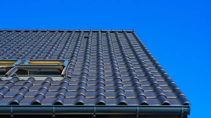 Vertical low angle closeup shot of the black roof of a building with a blue background